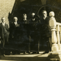 Cinq hommes devant un bâtiment