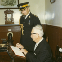 Un homme signe un livre en compagnie d'un autre homme